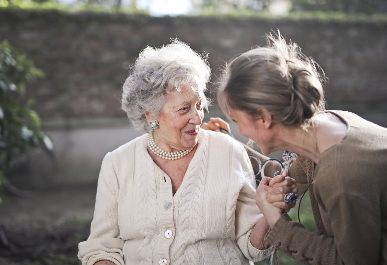 Services Joyful interaction between an elderly woman and her granddaughter in a sunny outdoor setting.