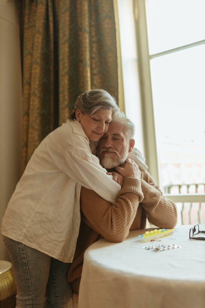 A senior couple shares a tender hug in a cozy indoor setting, radiating love and affection.