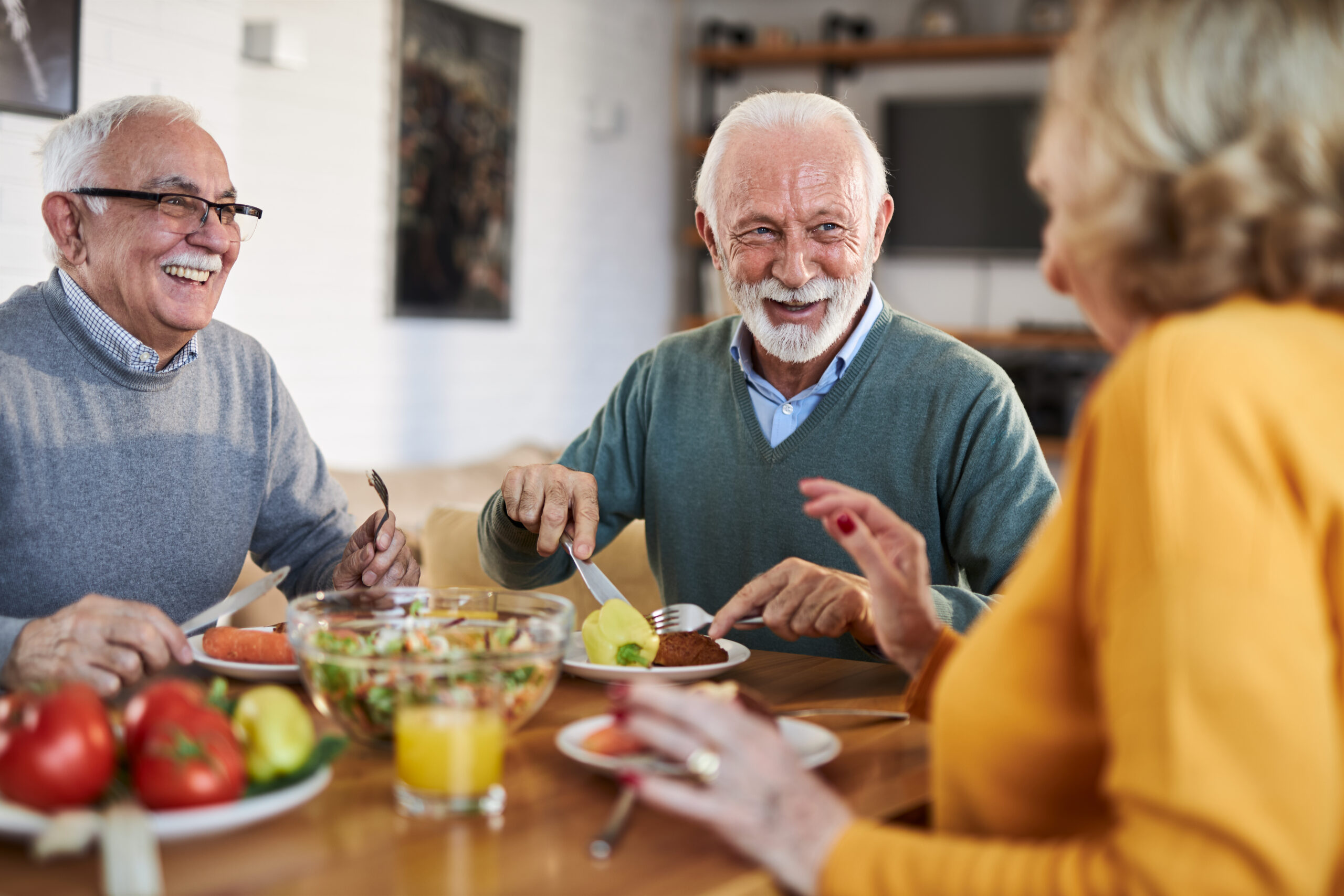 group of happy senior friends talking while having a meal at dining table. group of happy senior friends talking while having a meal at dining table.